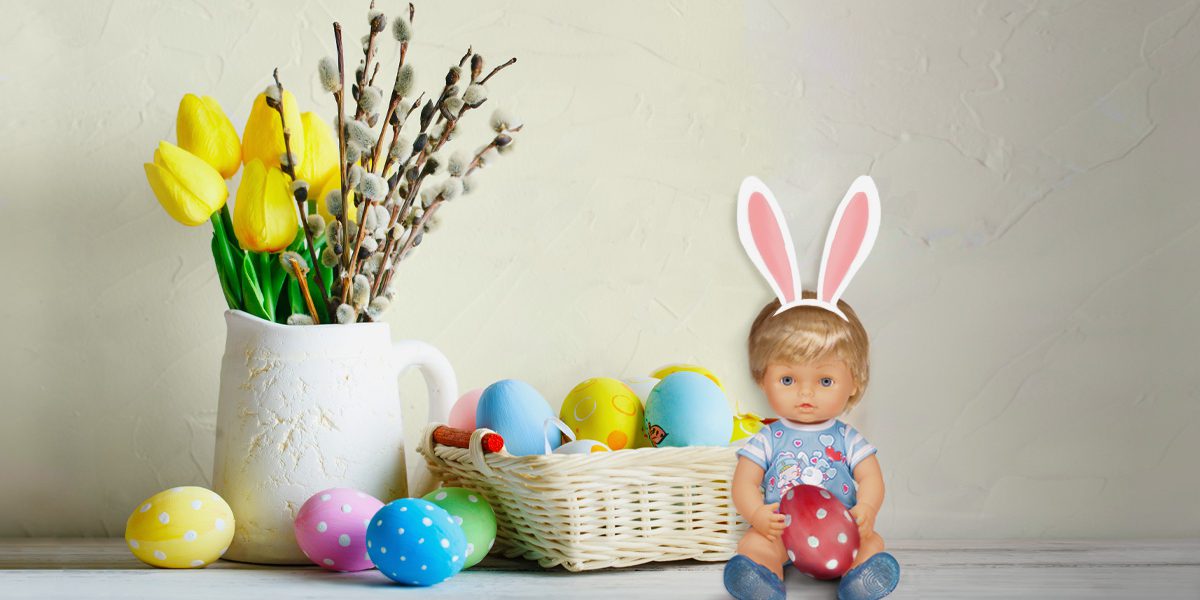 Cicciobello davanti a un cestino pieno di uova di Pasqua decorate