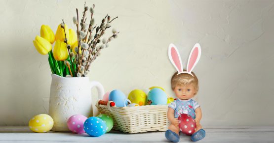 Cicciobello davanti a un cestino pieno di uova di Pasqua decorate