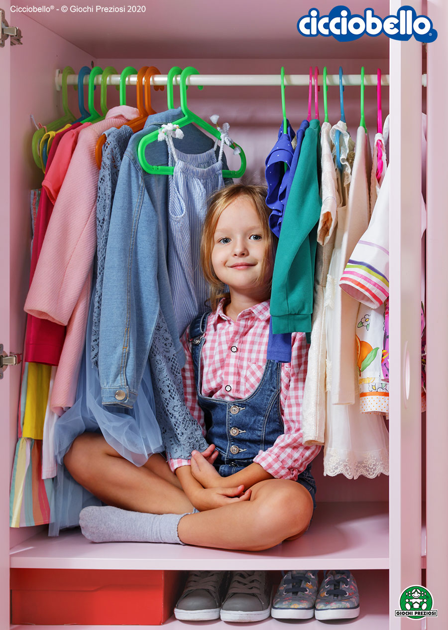 Bambina seduta sorridente all'interno del suo armadio