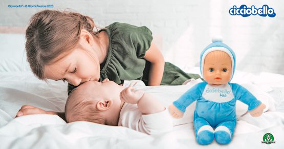 Una bambina bacia un neonato sulla fronte, a fianco a loro c'è Cicciobello Bebè Bellissimo